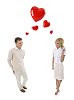 Couple in white with shy smiles and flying red hearts between them