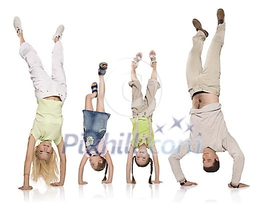 Mom, two daughters and dad doing handstand in white space