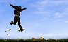 Boy jumping in grass with fallen maple leafs