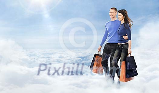 Young happy couple walkin in clouds with many shopping bags