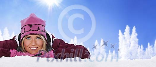Beautiful girl lying on snow on a sunny day