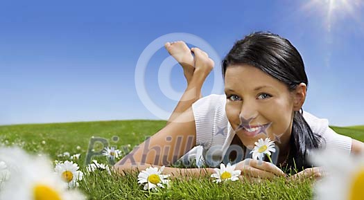 Beautiful girl lying in grass surrounded by daisies