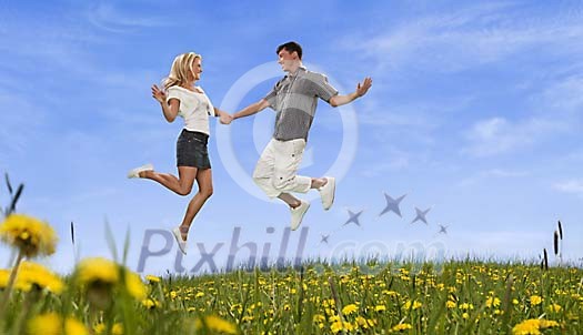 Young couple jumping on a summery meadow