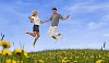 Young couple jumping on a summery meadow