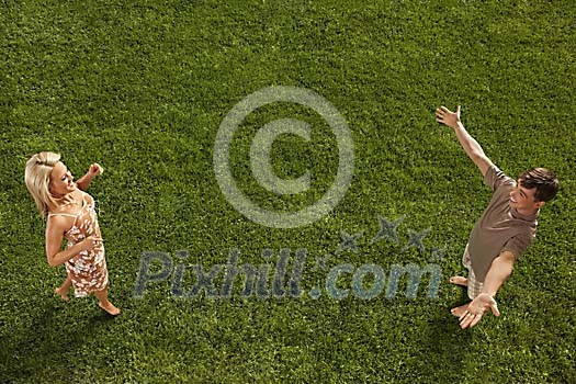 Young woman running towards young man on lawn