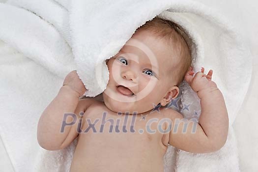 Baby girl lying on white towel