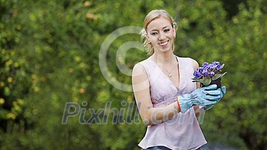 Portrait of a woman in garden holding a flowerpot