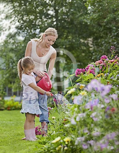 Mother and daughter watering flowers together
