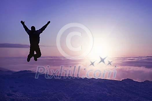 Person jumping on top of a mountain above the clouds