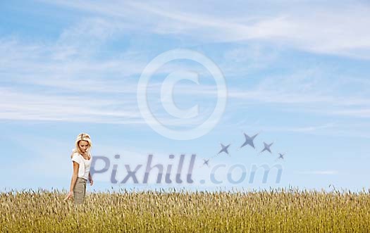 Beautiful woman walking alone in a summery field Beautiful woman walking alone in a summery field