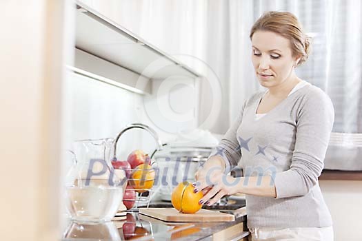 Woman in the kitchen cutting orange Woman in the kitchen cutting orange