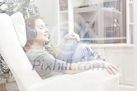 Woman sitting in the armchair listening to music Woman sitting in the armchair listening to music