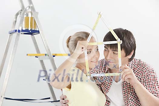 Couple holding a folding ruler shaped as a house Couple holding a folding ruler shaped as a house