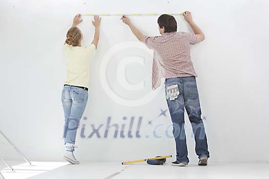 Couple taking measures of the wall Couple taking measures of the wall