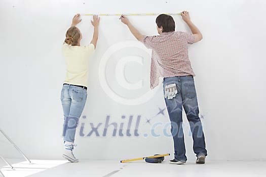 Couple taking measures of the wall