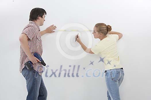 Couple at the wall choosing a place to drill a hole