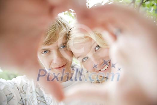 Couple looking through a heart shape made with their hands