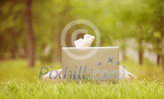 Woman lying on grass and using her laptop