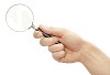 Clipped male hand holding a magnifying glass