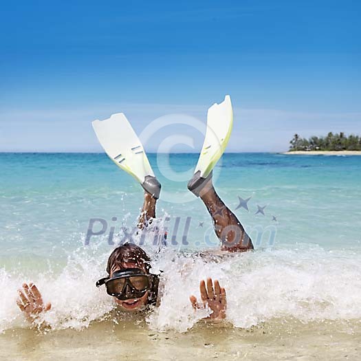Man in small waves on the beach with snorkeling equipment