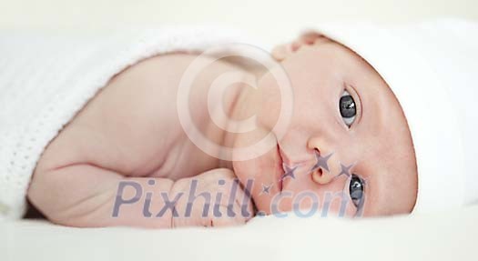Baby lying on white blankett Baby lying on white blankett