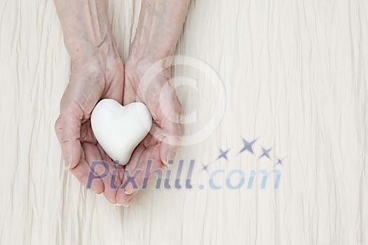 Old hands holding a heart