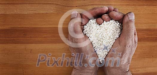 Older male hands holding rice shaped as a heart Older male hands holding rice shaped as a heart