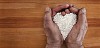 Older male hands holding rice shaped as a heart