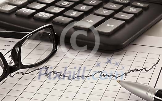 Eyeglasses, pen and calculator on top of chart Eyeglasses, pen and calculator on top of chart