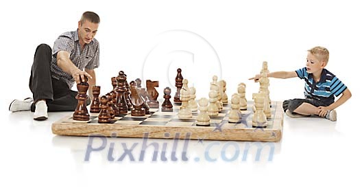 Father and son playing chess on a giant size chessboard