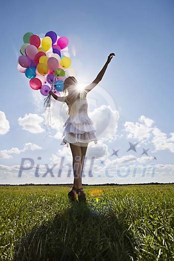 Girl dancing with balloons on the grass