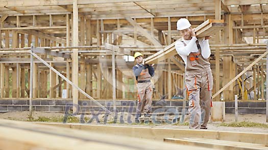 Constructors at a construction site carrying wood
