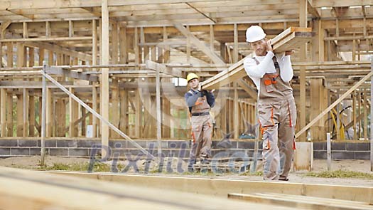 Constructors at a construction site carrying wood Constructors at a construction site carrying wood