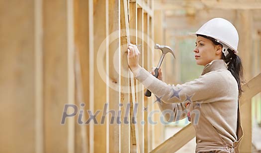 Female constructor hammering a nail