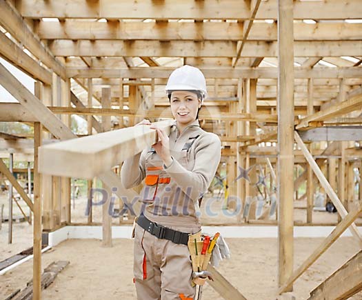Female constructor carrying wood Female constructor carrying wood