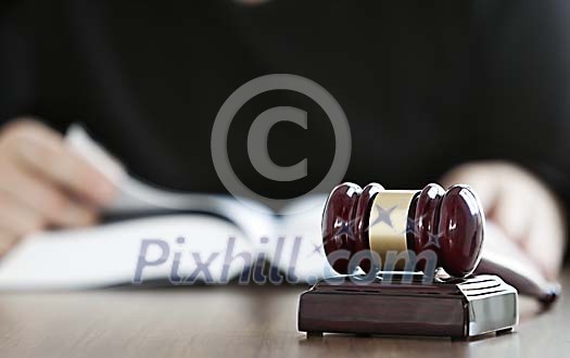 Judge gavel on table and judge looking at the book on the background Judge gavel on table and judge looking at the book on the background