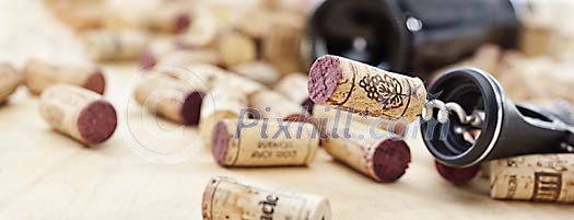 Red wine bottle, corkscrew and corks in shallow focus