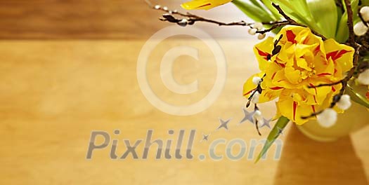 Vase of yellow tulips and pussy willow on a wooden table