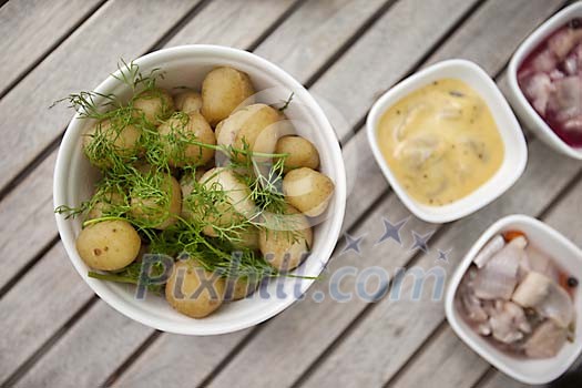 Boiled potatoes with dill and herring on table outside