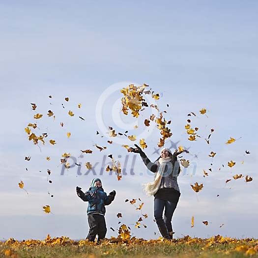 Mother and son throwing autumn leaves up in the sky