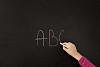 Hand writing on blackboard with piece of chalk