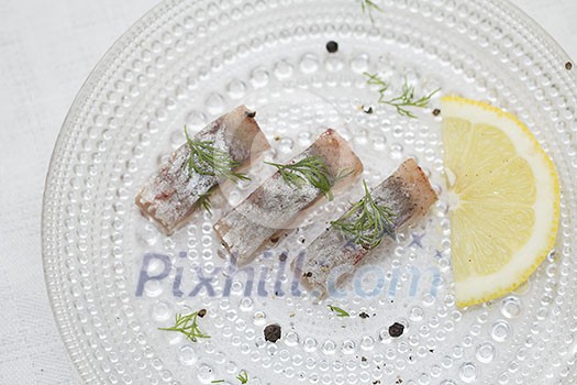 Pieces of herring with lemon slice on a plate Pieces of herring with lemon slice on a plate