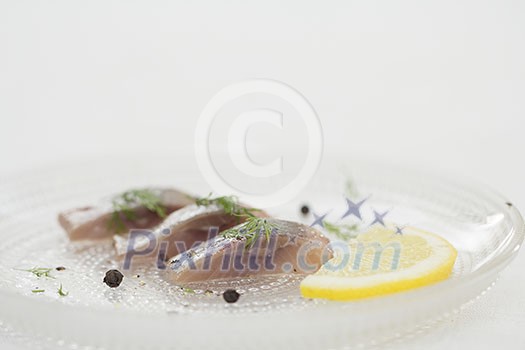 Pieces of herring with lemon slice on a plate Pieces of herring with lemon slice on a plate
