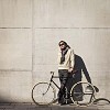 Hipster man with a bike by the wall