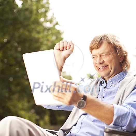 Middle aged man holding ipad, sitting outside