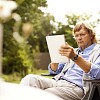 Middle aged man sitting outside, holding ipad