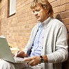 Man sitting by the wall with laptop