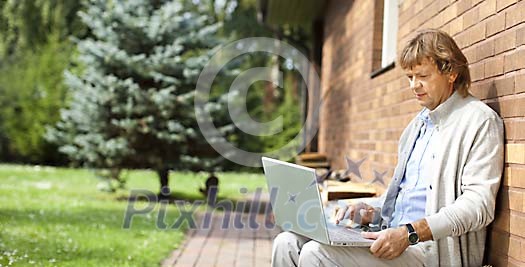 Man sitting by the wall with laptop