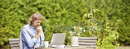 Man sitting in the garden with laptop