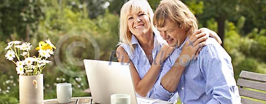 Older couple sitting outside with a laptop